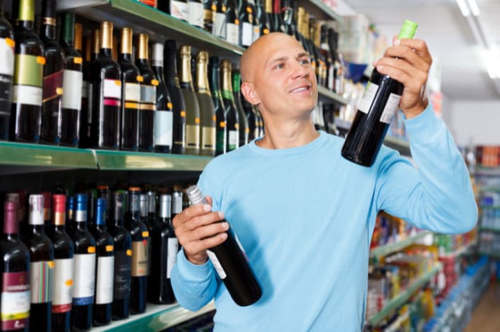 client qui choisit un vin dans un supermarché