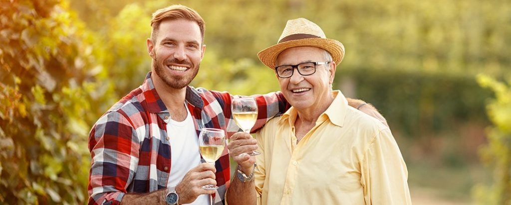 Un père et son fils trinquant un verre de vin à la main à l'occasion de la fête des pères