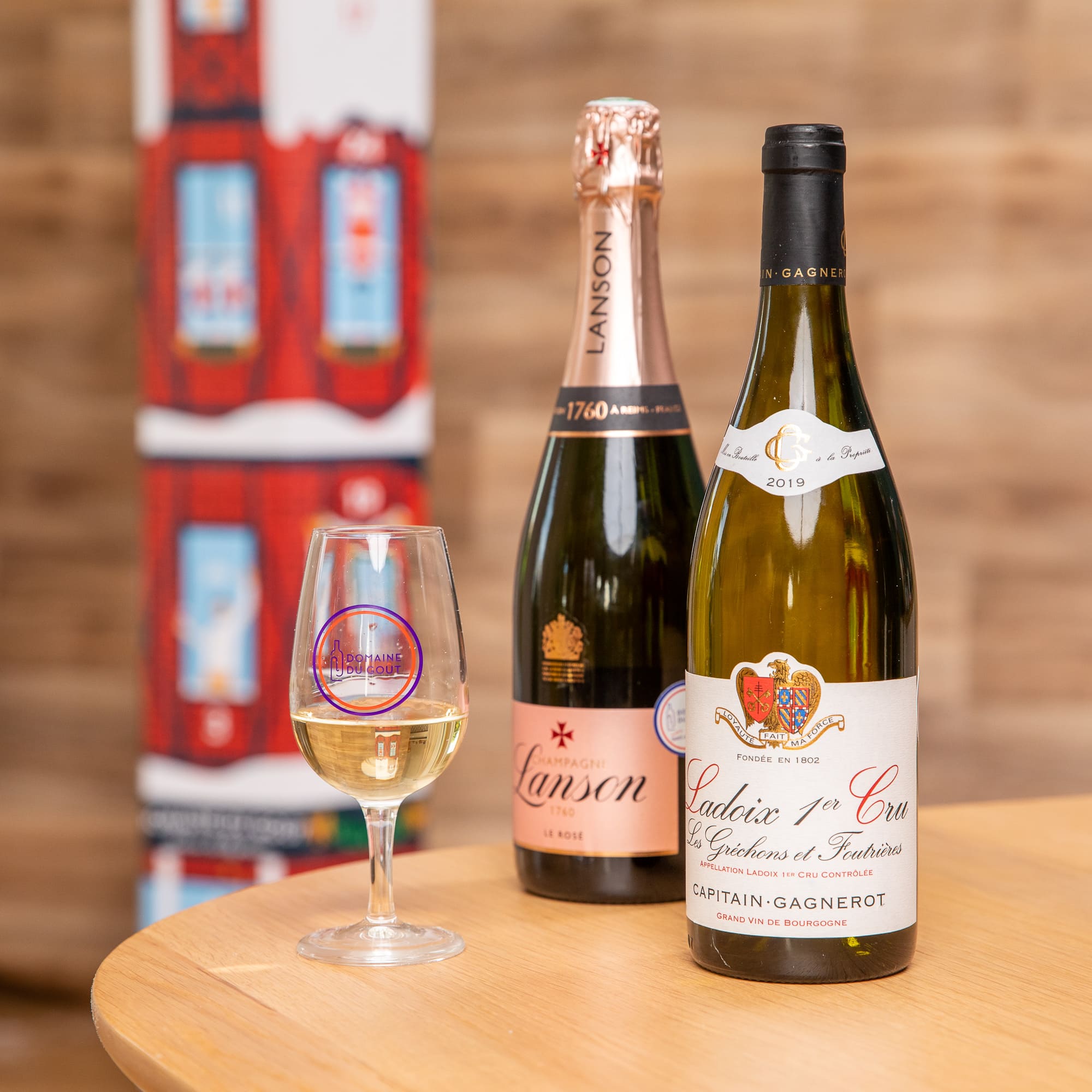 Une bouteille de champagne et une bouteille de vin premier cru avec un verre dé dégustation de vin blanc.